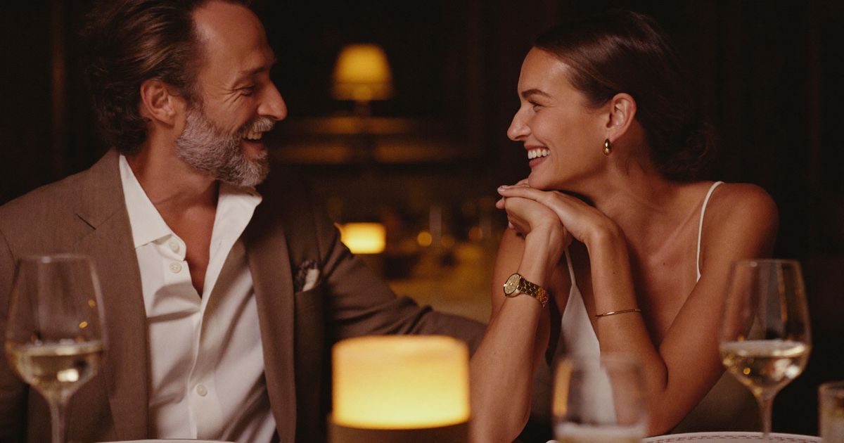 Un homme et une femme d’une cinquantaine d’années rient à une table éclairée à la bougie