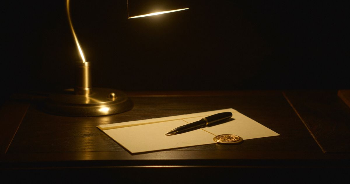 Un stylo plume posé sur une lettre scellée à la cire, sous une lampe de bureau dorée